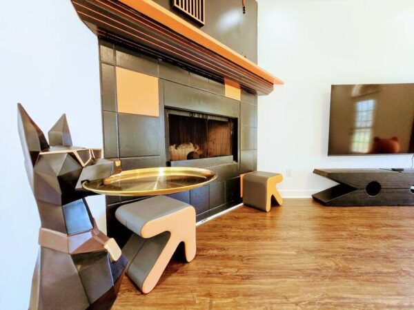 A stylish living room features a geometric black dog statue beside a contemporary coffee table, a sleek fireplace, and a modern TV unit.